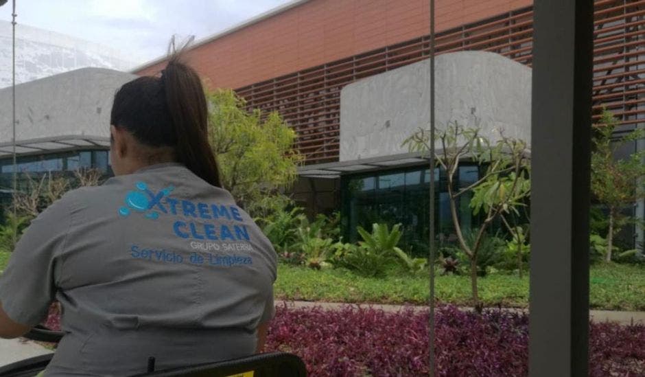 Una mujer limpiando con una camisa de Xtreme Clean, en una mesa de afuera de un edificio