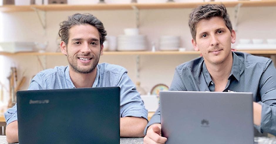 un joven moreno con barba y un hombre caucásico con pelo claro frente a una computadora