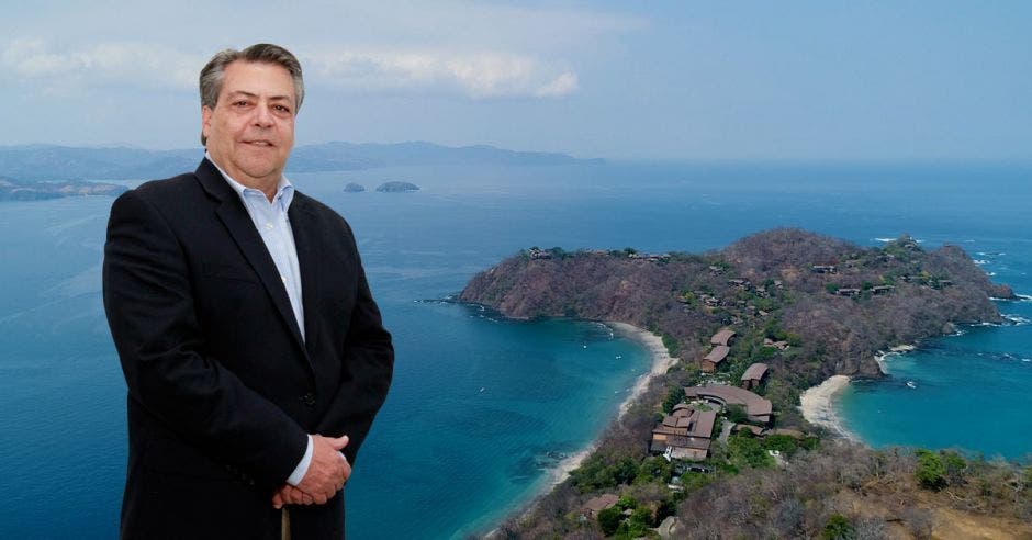 Un señor de avanzada edad posa frente un golfo de mar cristalino