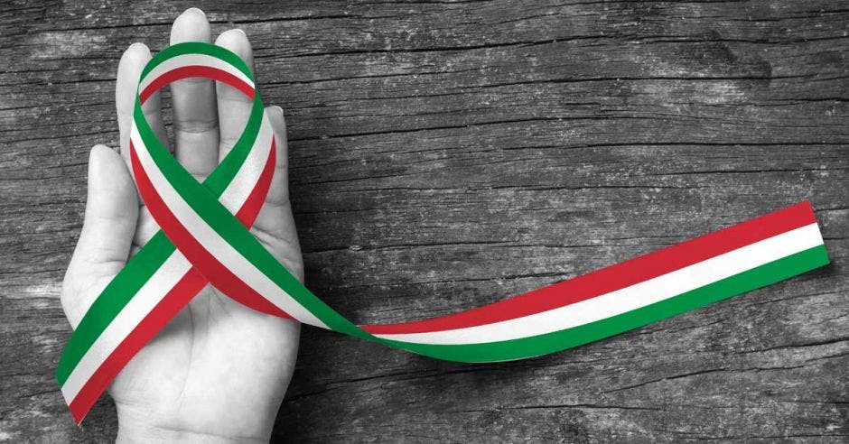 Una mano sostiene un lazo con los colores de la bandera italiana