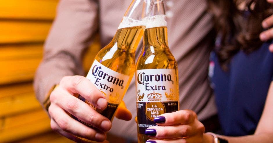 Dos jóvenes toman una cerveza marca corona