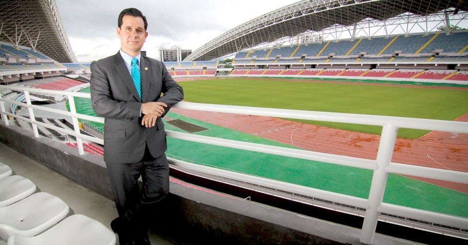Un hombre de traje gris y corbata celeste posa en las barandas del estadio nacional