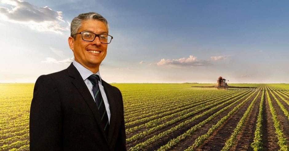 Un señor de mediana edad posa frente a un campo de agricultura