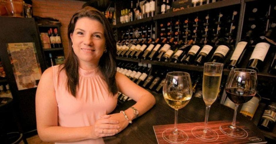 Una mujer de mediana edad posa junto a varias copas de vino