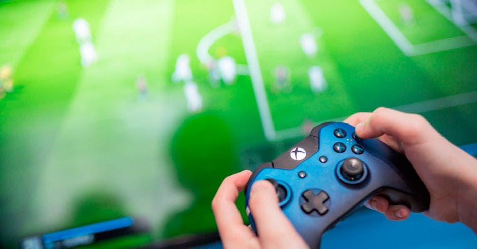 Un control de Xbox One, con una pantalla con un juego de fútbol