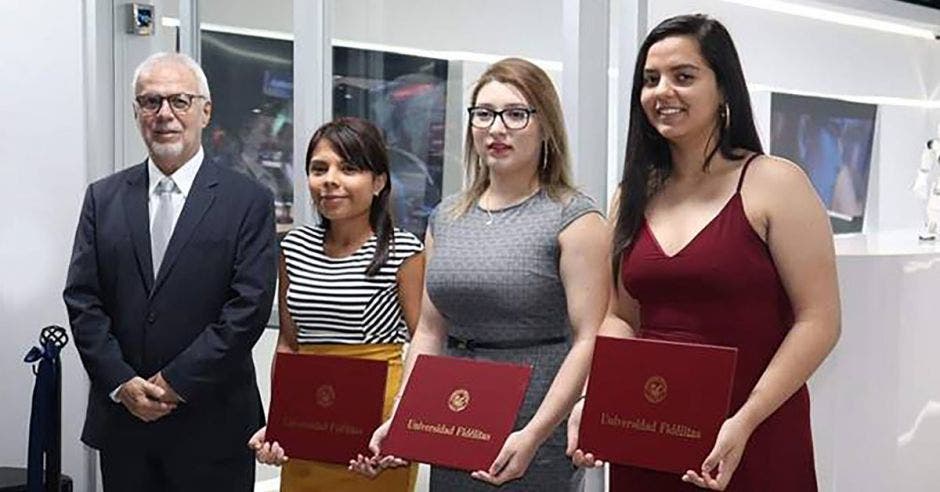 Roberto Rodríguez, rector de U Fidélitas en una graduación junto a tres estudiantes