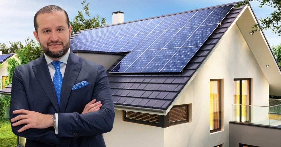 Un hombre posa junto a una casa con paneles solares