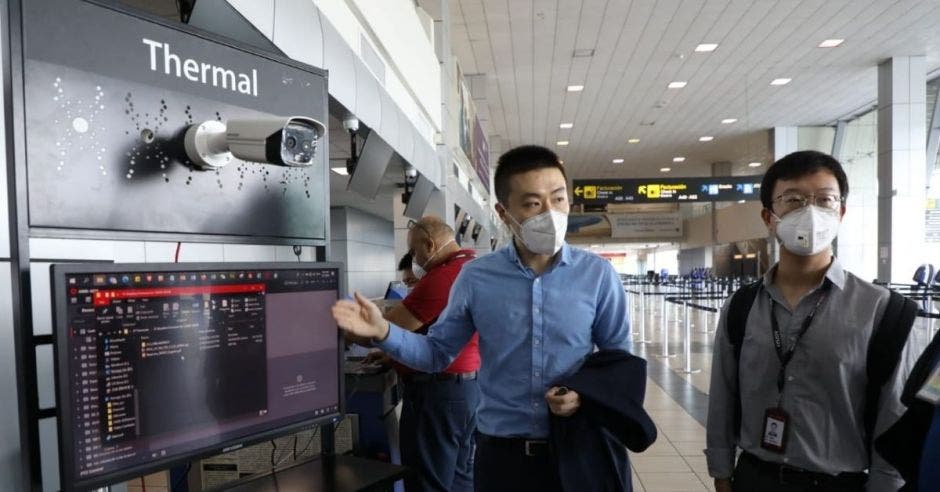 Un hombre asiático con mascarilla manipula una cámara térmica