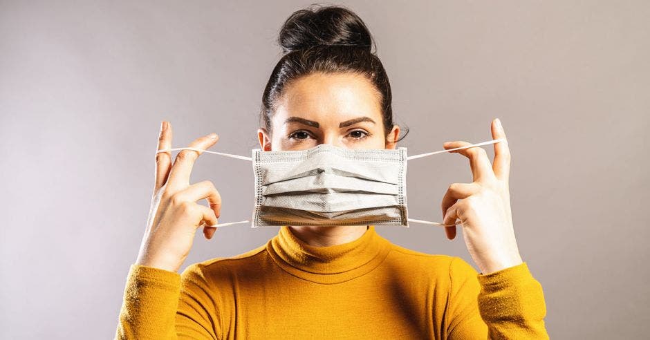 Una mujer utiliza una máscara desechable color blanco