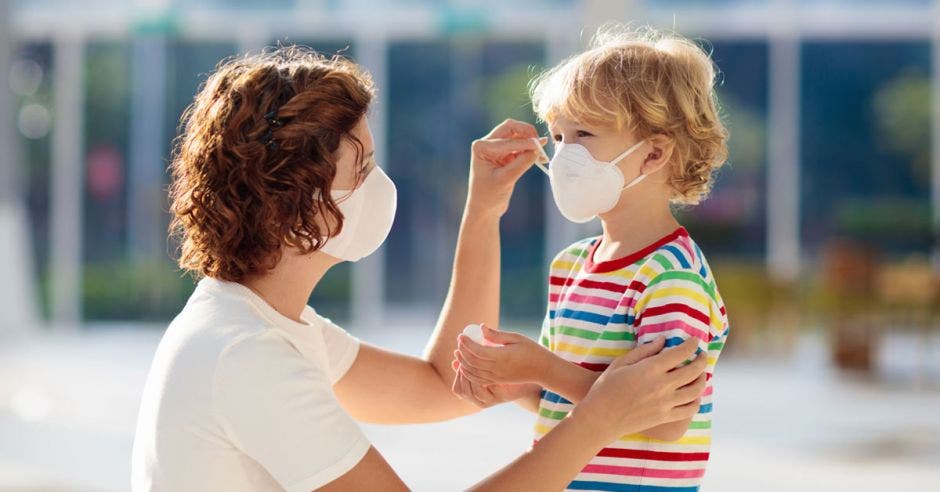 Mamá poniéndole mascarilla al hijo