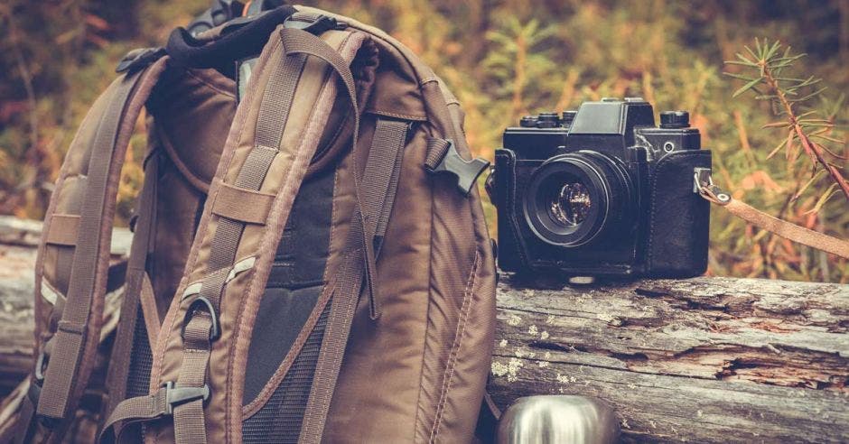 Una mochila, una cámara fotográfica y un termo de aluminio con café