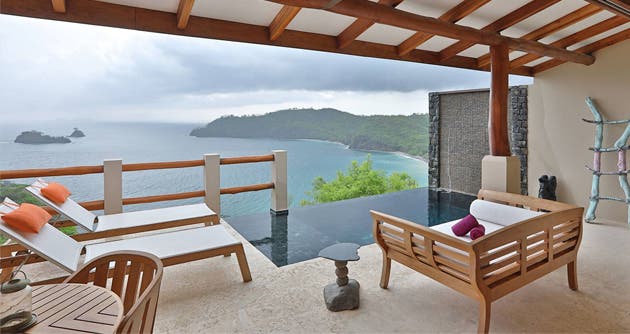 Dos sillas, una piscina infinita y una vista amplia al mar