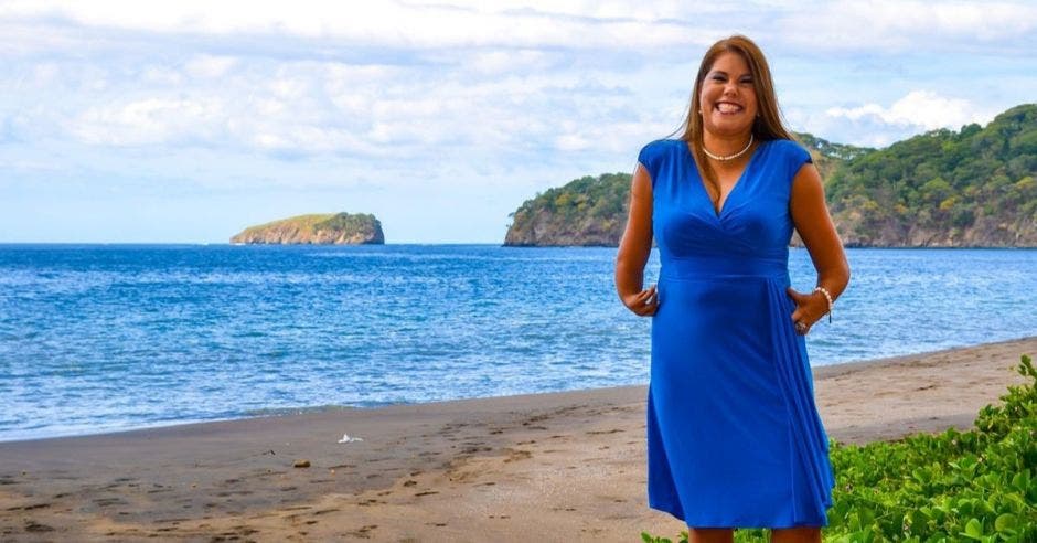 Una mujer con vestido azul posa en la playa