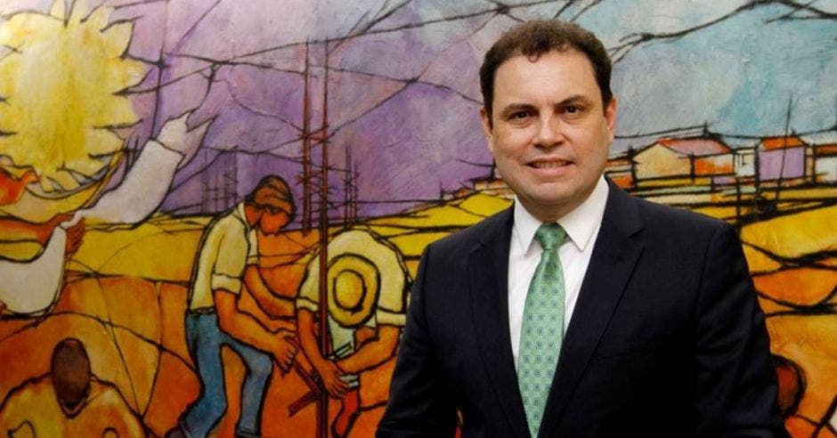 Carlos Ricardo Benavides, diputado de Liberación, posa para una fotografía con una pintura de fondo