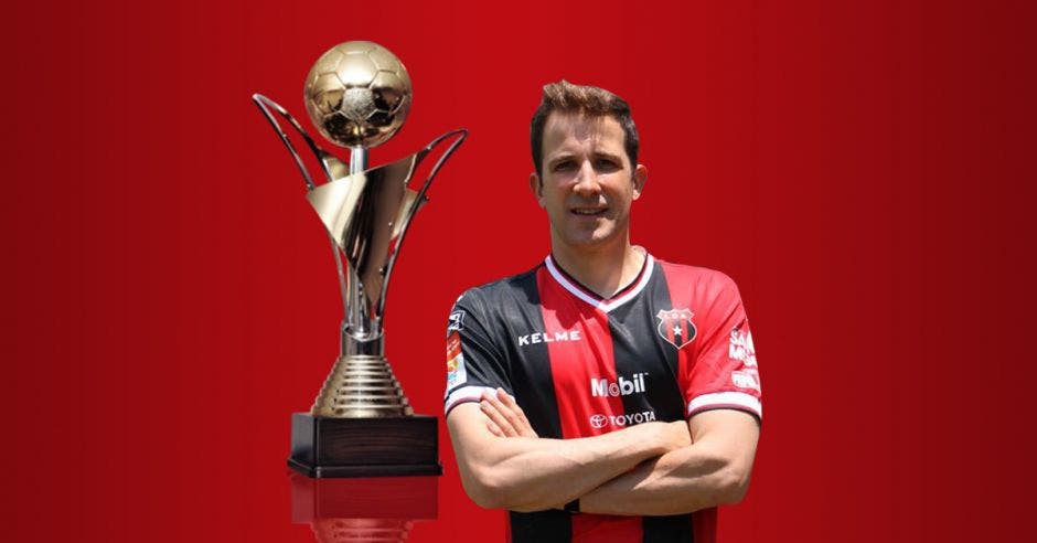 Hombre de brazos cruzados posa frente a un trofeo