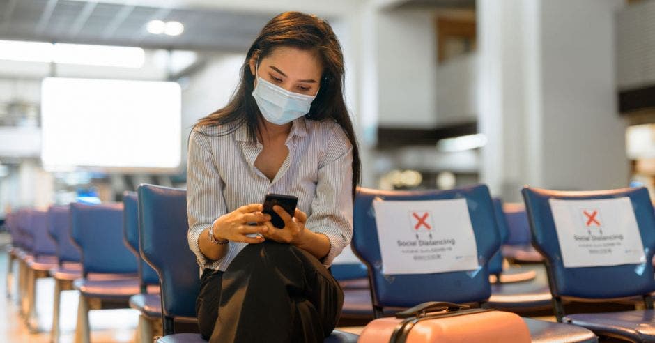 Una mujer con mascarilla en la sala de abordaje de un aeropuerto