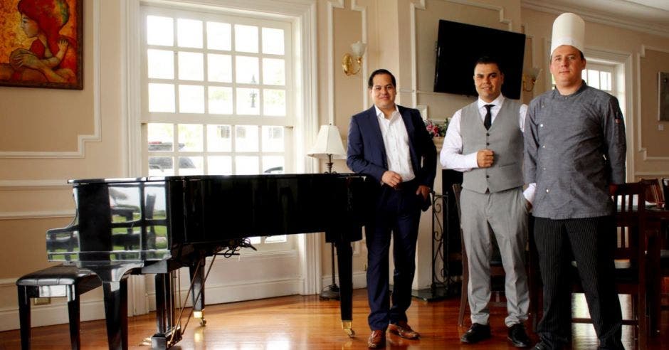 tres hombres posan junto a un piano