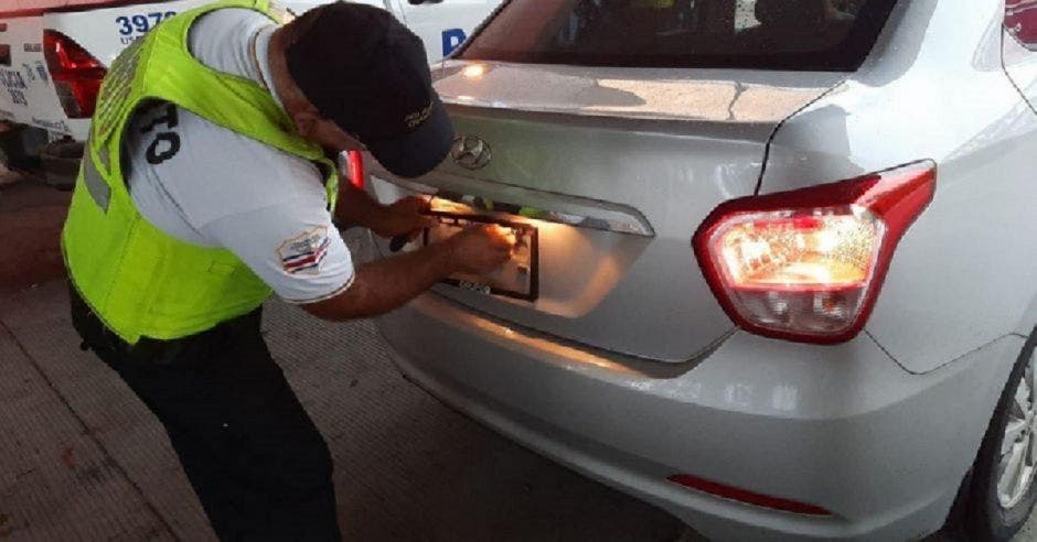 Oficial de tránsito aplicando el retiro de placas en un vehiculo