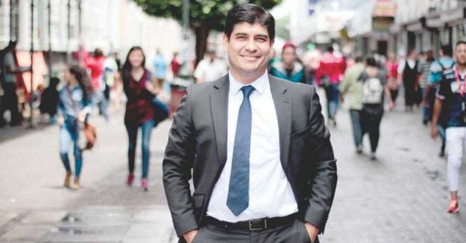 Carlos Alvarado vestido de traje en el medio de San José