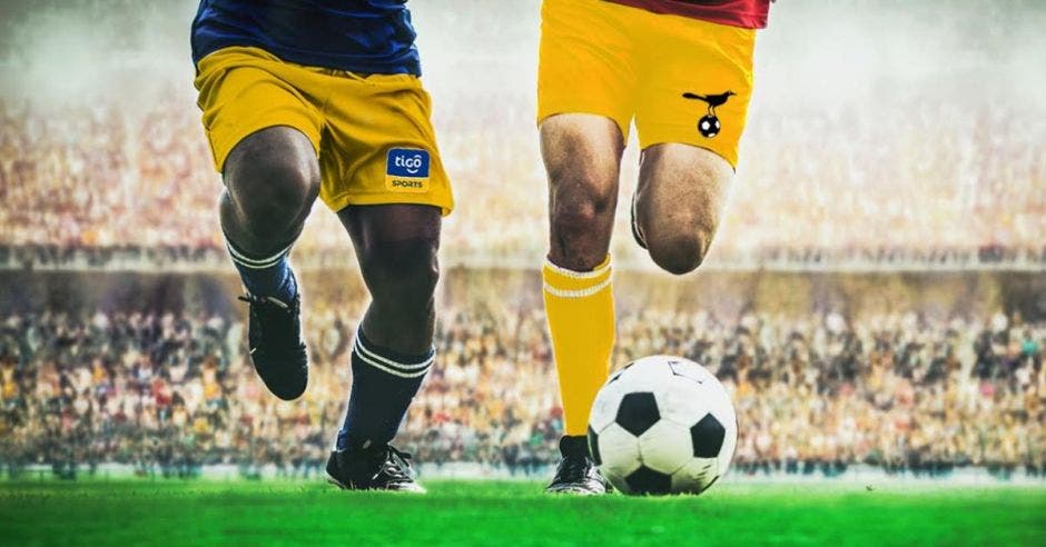 Dos pares de piernas corriendo detrás de un balón de fútbol