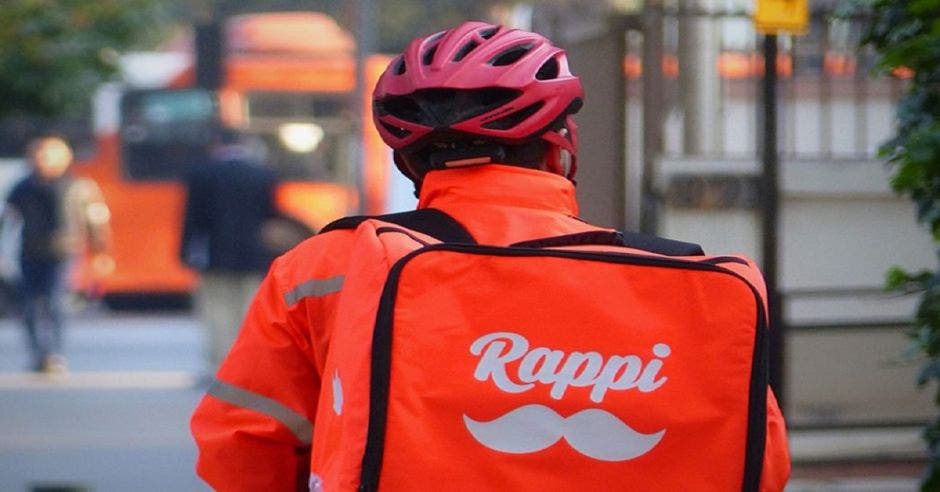 Hombre con casco y moto laborando en Rappi