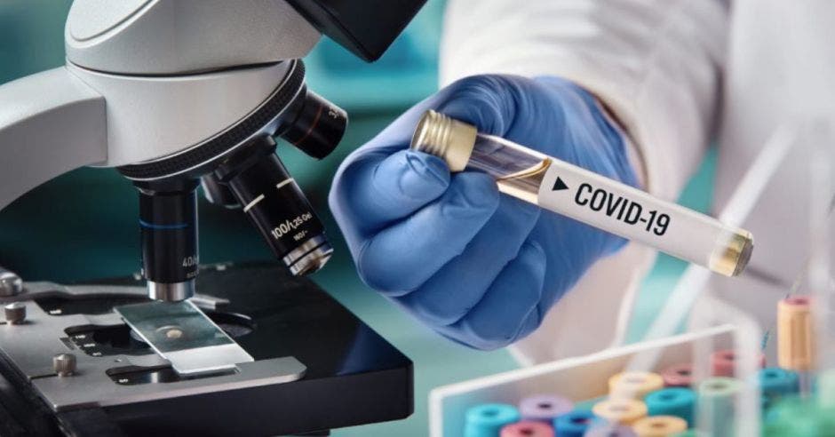 Persona con prueba Covid, guantes y microscopio