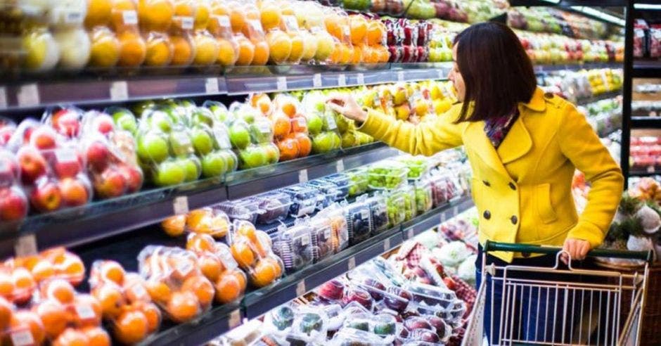 Mujer con carrito de supermercado escoge frutas