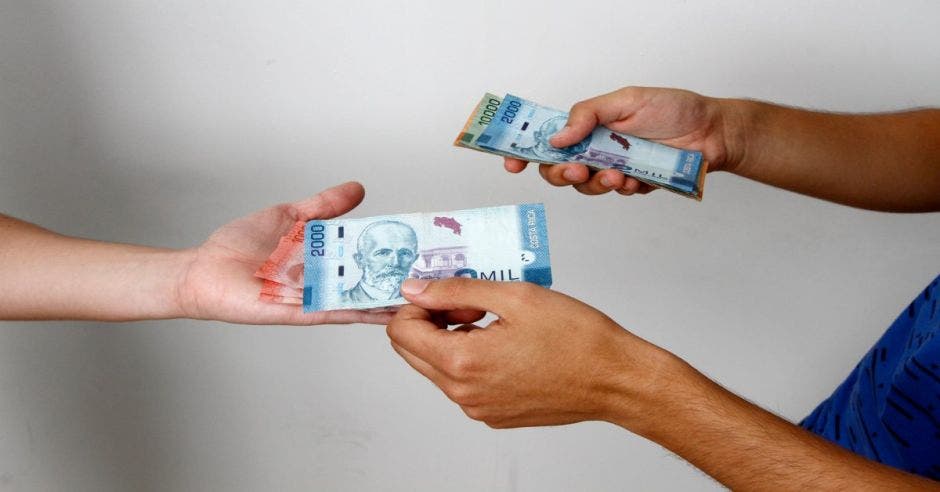 Persona le da a otra billetes en la mano