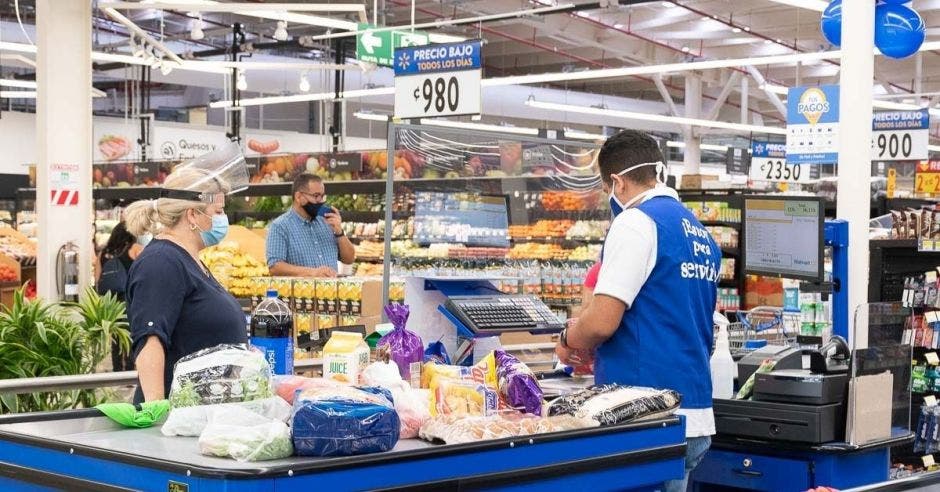 Un cajero atiende a una mujer desde el mostrador de un supermercado