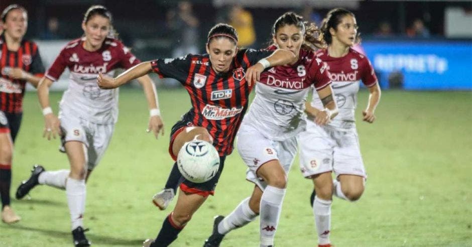 futbol femenino jugándose con dos mujeres disputando un balón