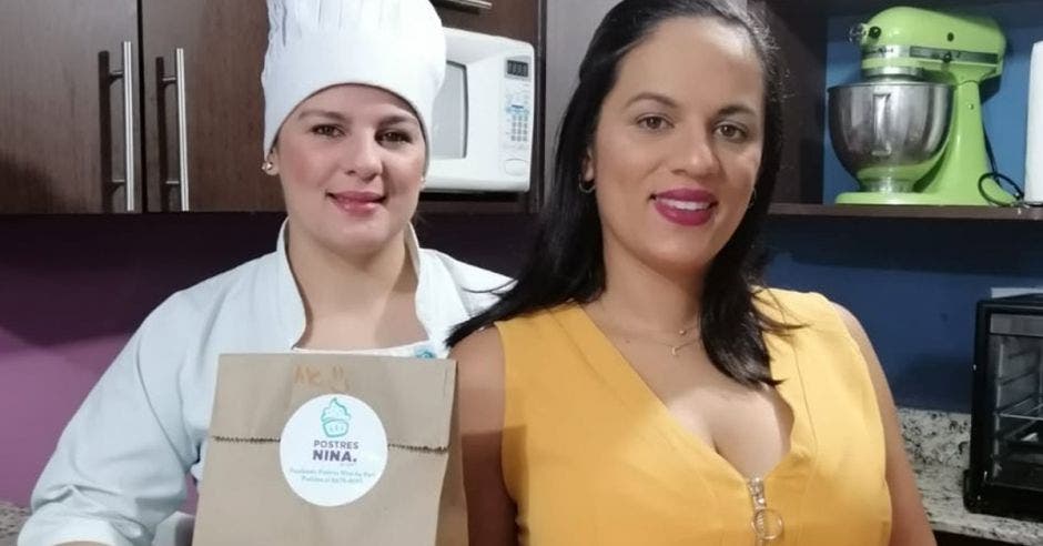 Emprendedoras posan, una con un sombrero de chef