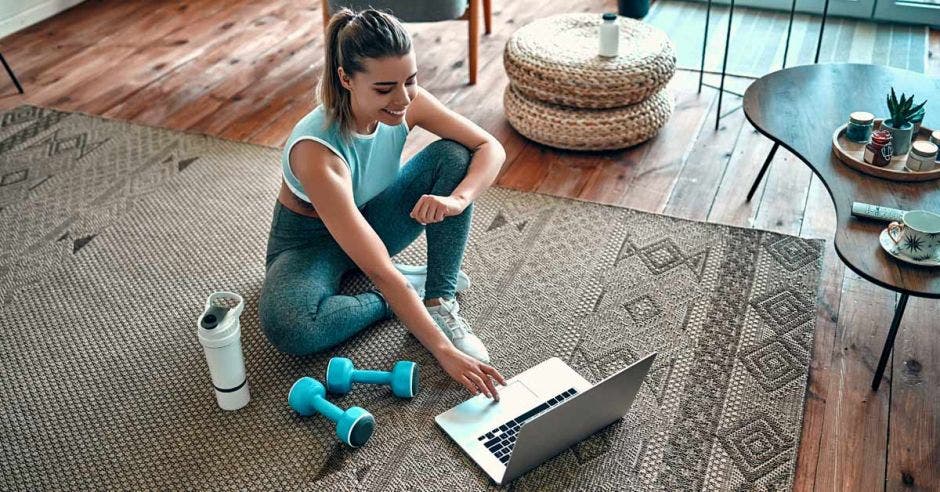 Una mujer haciendo ejercicio frente a una computadora