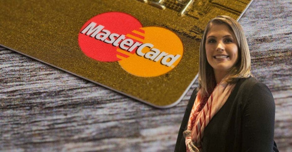 Mujer posa frente a tarjeta de Mastercard