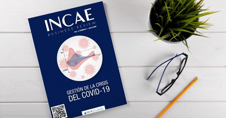 Vemos la edición del INCAE Business Review en un escritorio junto con anteojos y lápices.