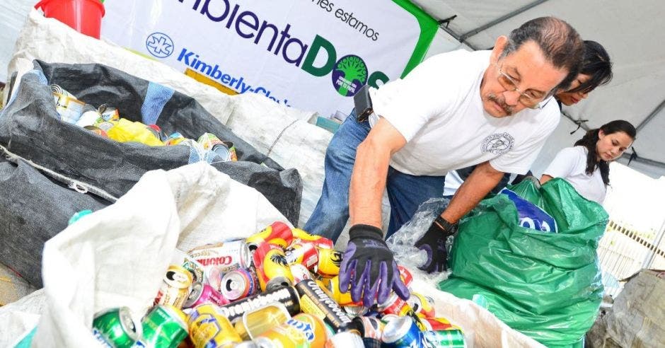 un hombre recolecta latas de cerveza en una bolsa de reciclaje