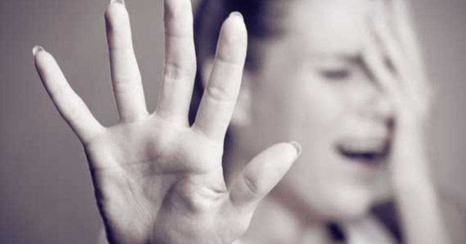 Mujer llorando con una mano pidiendo que se detenga