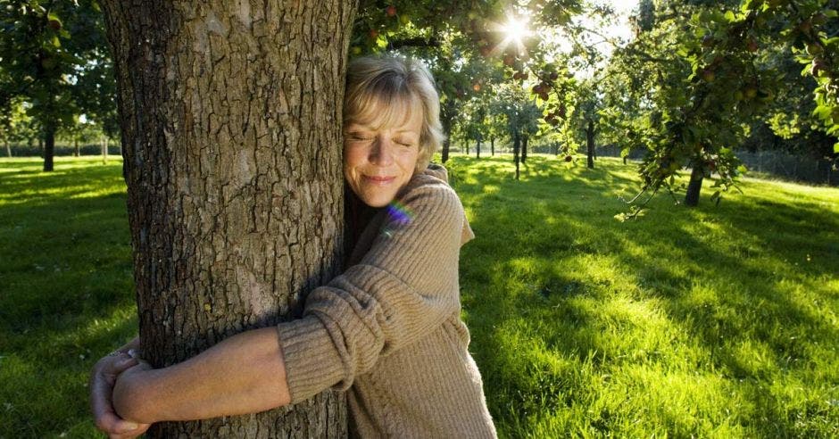 Una señora está abrazando a un árbol