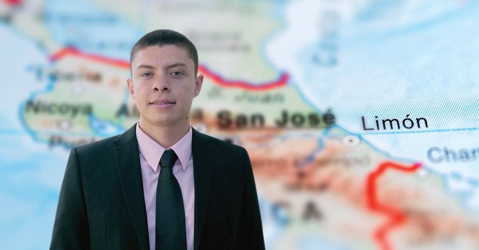 Un hombre de saco y corbata posa frente a un mapa de Limón, Costa Rica