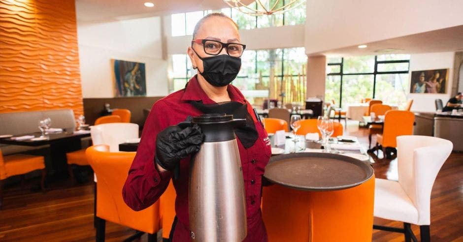 Vemos a una mesera con mascarilla sosteniendo café