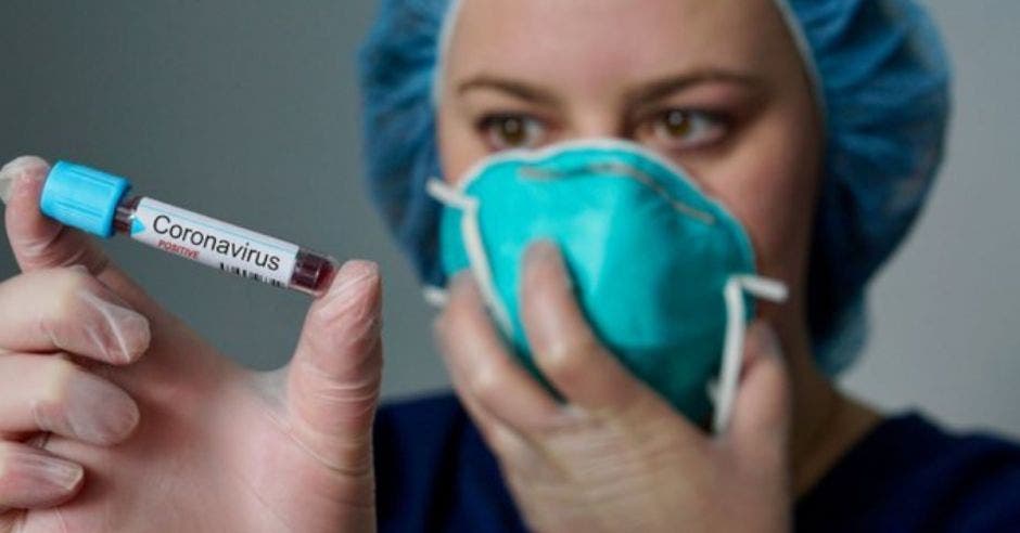 Mujer viendo prueba de sangre mientras tiene mascarilla