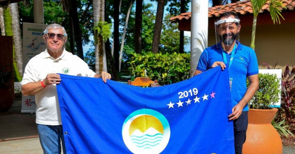 Dos hombres sostienen una bandera azul