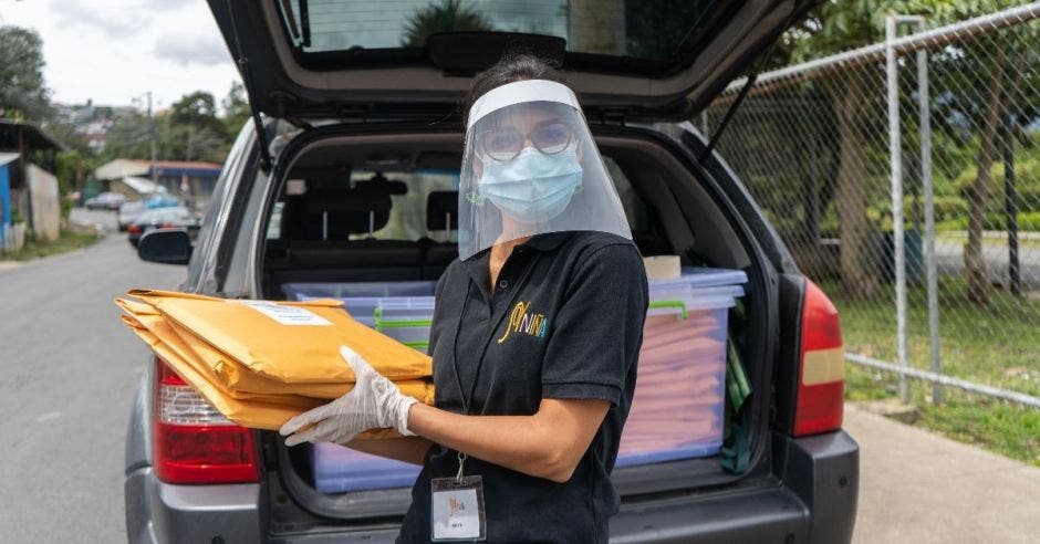 Una mujer con mascarilla sostiene unos documentos