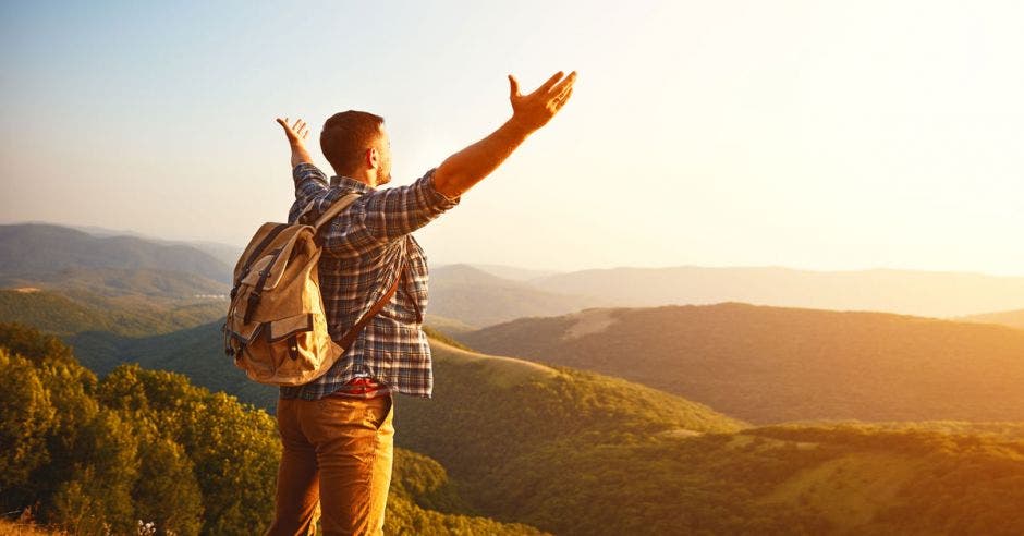 Un turista con las manos abiertas al horizonte