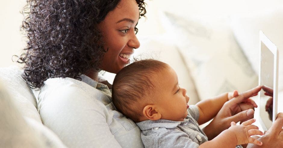 Vemos a una mujer negra con un bebé viendo el celular