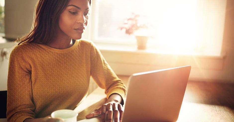 Una mujer afrodescendiente frente a una computadora color gris