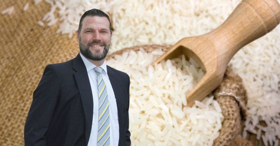 Un hombre con saco y corbata junto a un saco de arroz