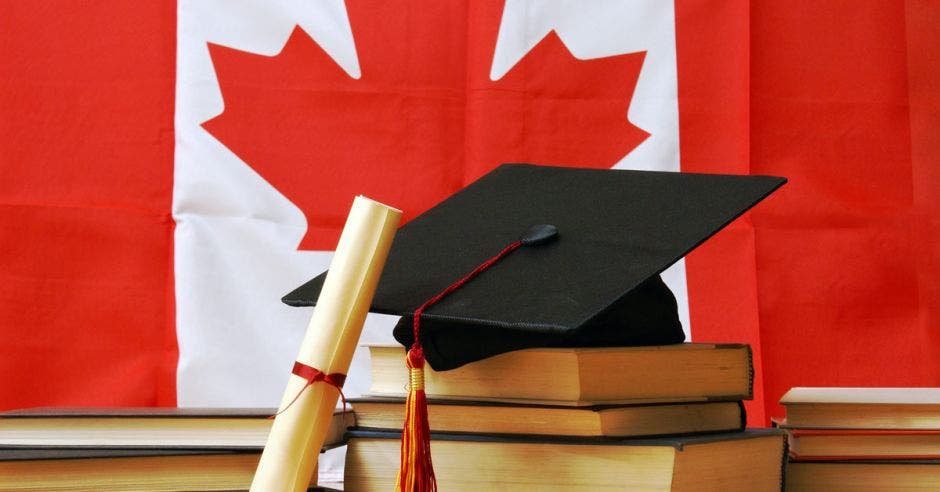 Vemos un diploma frente a la bandera de Canadá