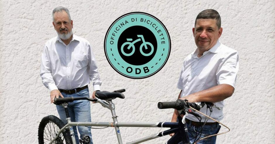 Dos hombres con camisa blanca junto a una bicicleta