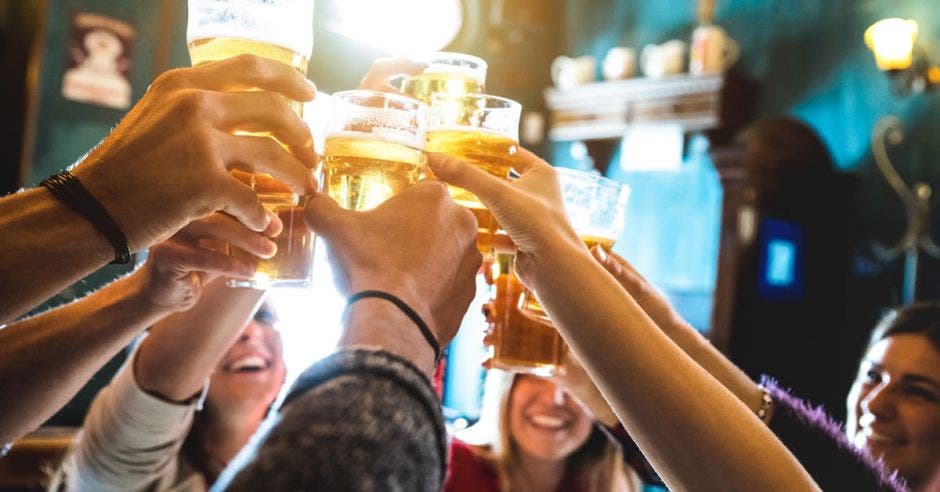 Un grupo de personas brinda con sus cervezas en el aire