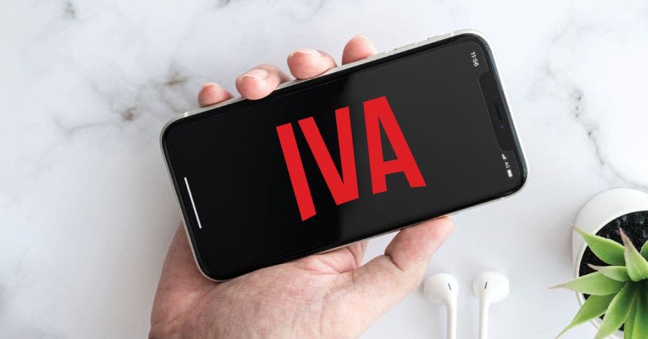 Una persona sostiene un celular que dice la palabra IVA